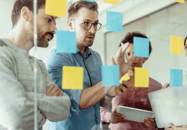 Group of people brainstorming and adding notes to a window